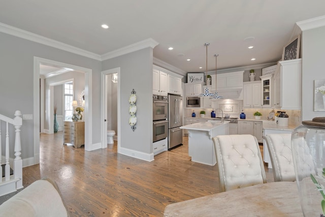 kitchen with a kitchen bar, white cabinetry, a center island, hanging light fixtures, and appliances with stainless steel finishes