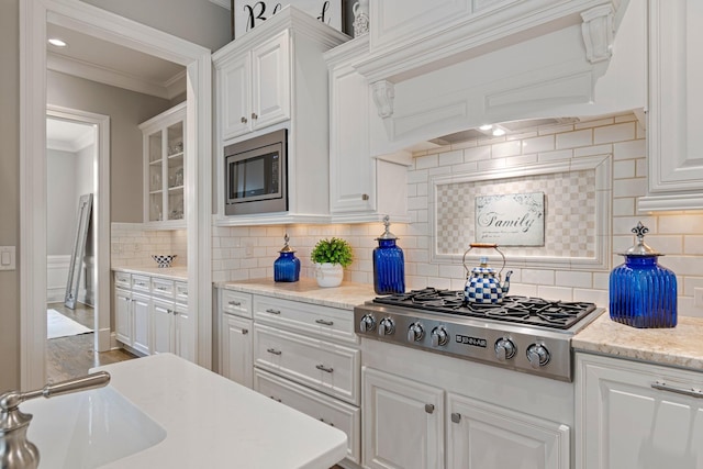 kitchen featuring white cabinetry, appliances with stainless steel finishes, crown molding, and custom range hood