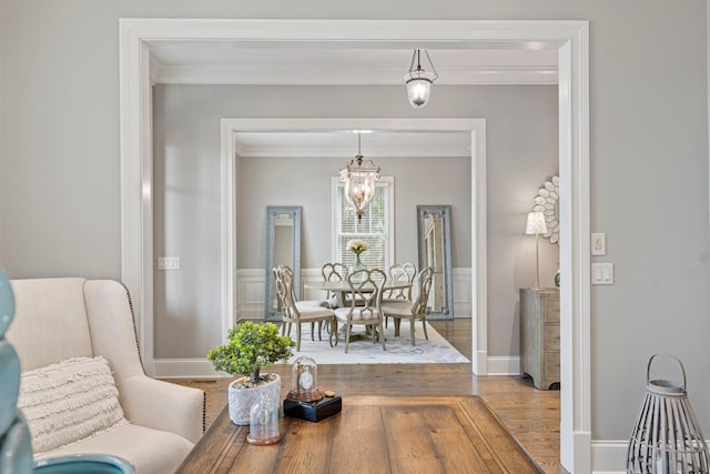 dining space featuring crown molding, wood-type flooring, and a notable chandelier