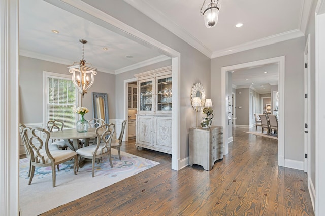 dining area with an inviting chandelier, dark wood-type flooring, and ornamental molding