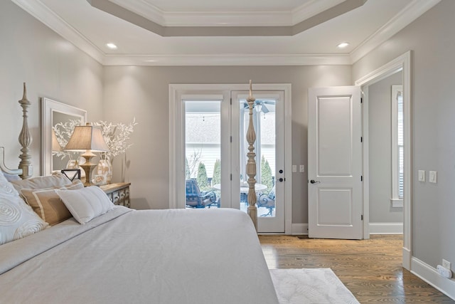 bedroom with access to exterior, hardwood / wood-style flooring, ornamental molding, and a raised ceiling