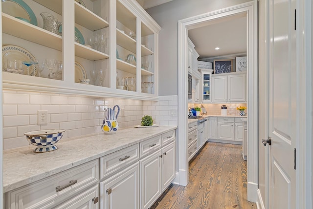 kitchen with decorative backsplash, light hardwood / wood-style flooring, light stone countertops, and white cabinets