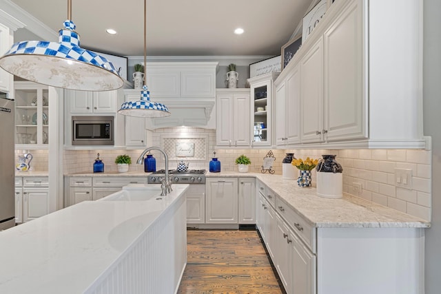 kitchen with pendant lighting, white cabinetry, light stone counters, light hardwood / wood-style floors, and stainless steel appliances