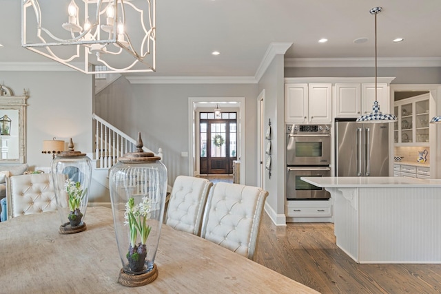 dining room featuring dark wood-type flooring, crown molding, and an inviting chandelier