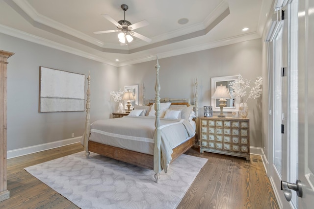 bedroom featuring crown molding, hardwood / wood-style floors, a tray ceiling, and ceiling fan