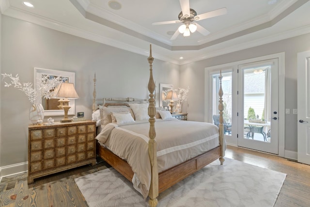 bedroom featuring wood-type flooring, ornamental molding, access to exterior, and a tray ceiling