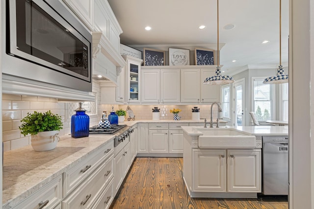 kitchen with sink, white cabinetry, crown molding, decorative light fixtures, and stainless steel appliances