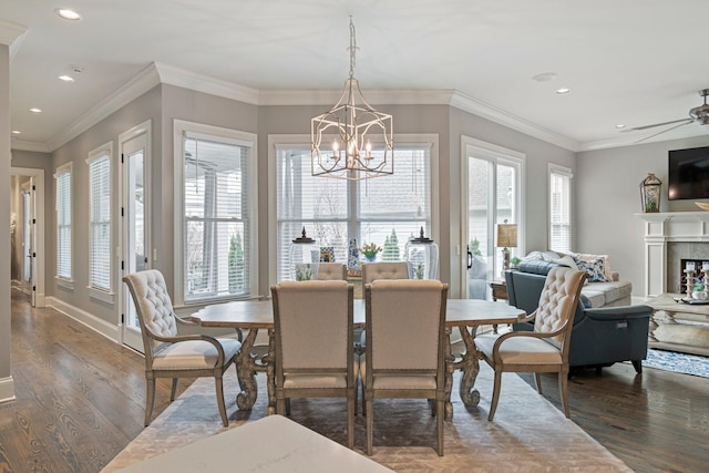 dining area with dark wood-type flooring, crown molding, and ceiling fan with notable chandelier