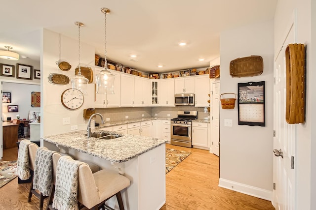 kitchen featuring appliances with stainless steel finishes, pendant lighting, sink, white cabinets, and kitchen peninsula