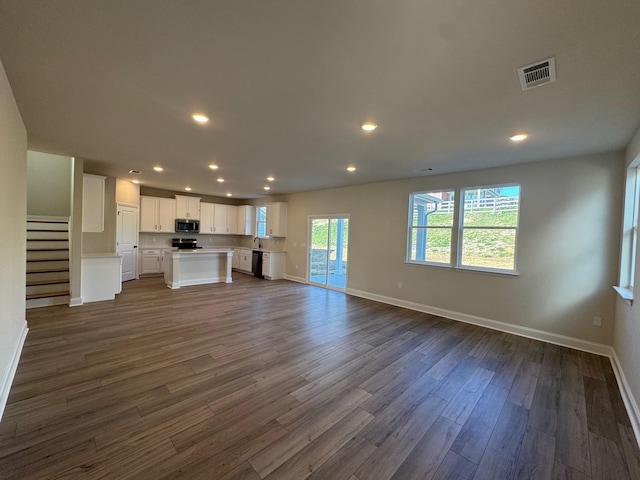 unfurnished living room featuring sink and dark wood-type flooring