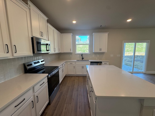 kitchen featuring sink, stainless steel appliances, a center island, and white cabinets