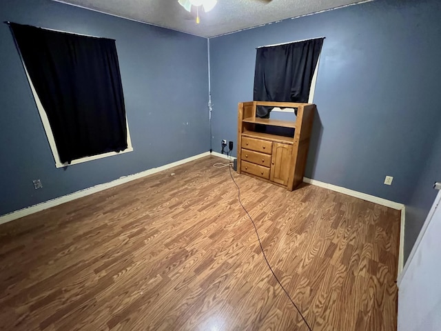 bedroom with hardwood / wood-style flooring, ceiling fan, and a textured ceiling