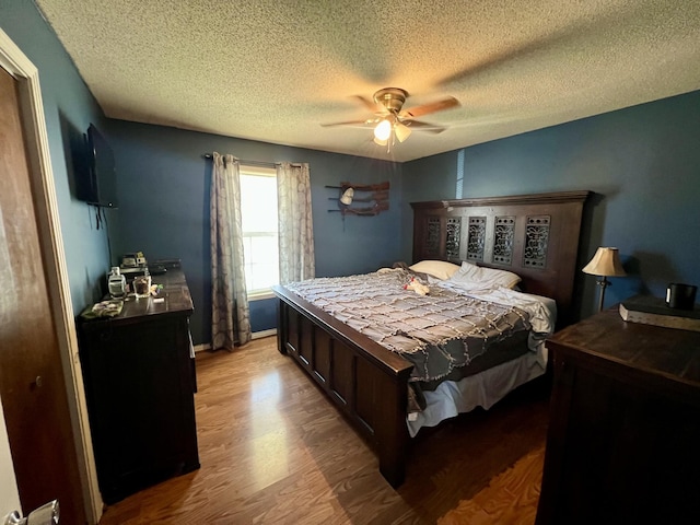 bedroom featuring ceiling fan, light hardwood / wood-style floors, and a textured ceiling