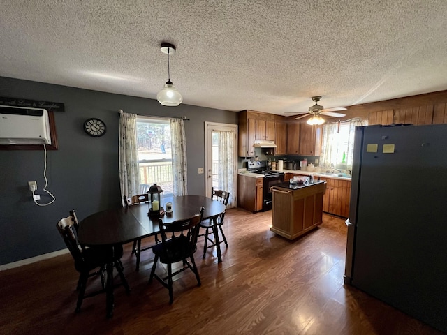 kitchen featuring range with electric cooktop, stainless steel refrigerator, dark hardwood / wood-style flooring, a wall unit AC, and pendant lighting