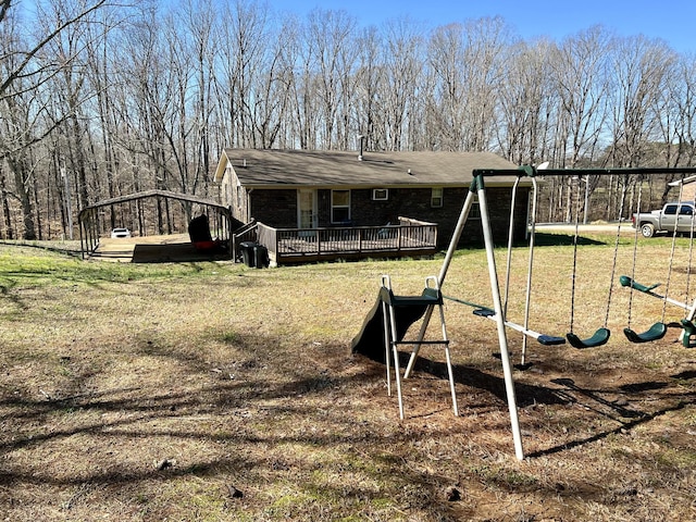 back of property with a playground, a deck, and a lawn