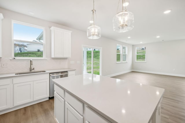 kitchen featuring decorative backsplash, dishwasher, light wood-style flooring, light countertops, and a sink