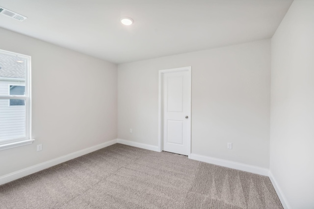 carpeted empty room featuring baseboards and visible vents