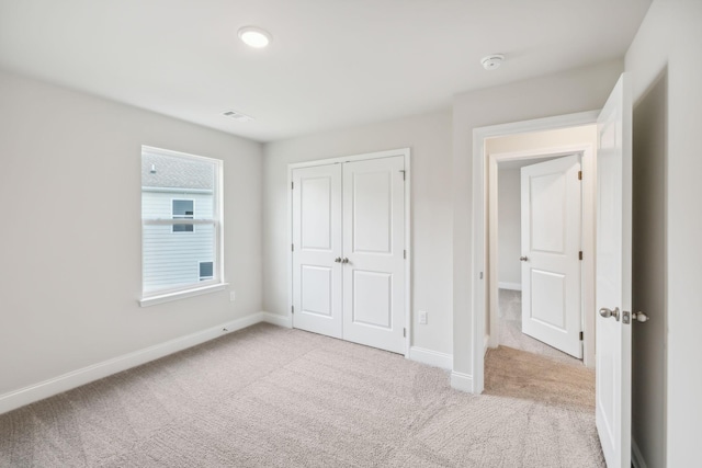 unfurnished bedroom featuring carpet, a closet, visible vents, and baseboards