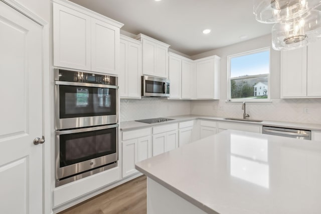 kitchen with stainless steel appliances, backsplash, a sink, and light countertops