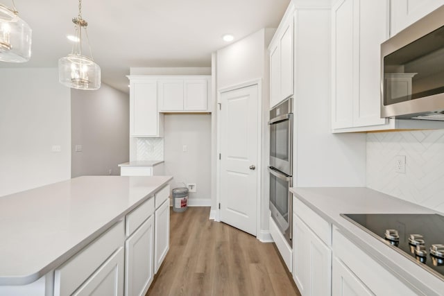 kitchen featuring stainless steel appliances, light countertops, and white cabinets