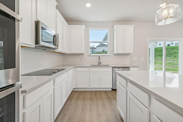 kitchen with stainless steel appliances, a healthy amount of sunlight, light countertops, and a sink