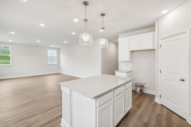 kitchen with tasteful backsplash, a center island, white cabinets, and light wood-style floors