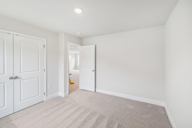 unfurnished bedroom with a closet, carpet, and baseboards