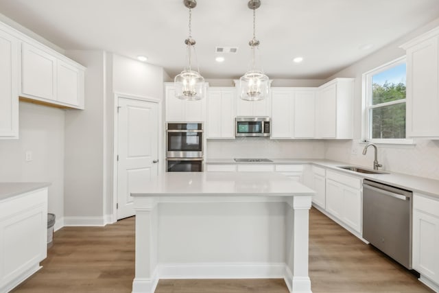 kitchen featuring a sink, visible vents, light wood-style floors, appliances with stainless steel finishes, and decorative backsplash