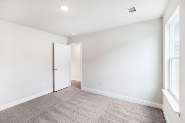 unfurnished room featuring light carpet, plenty of natural light, baseboards, and visible vents