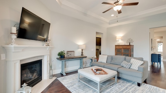 living room featuring hardwood / wood-style floors, a tray ceiling, and ceiling fan