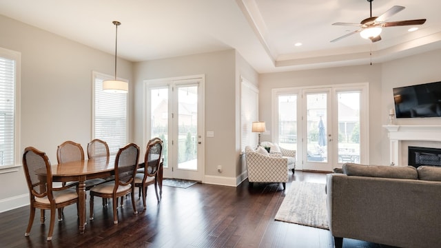 dining area featuring dark hardwood / wood-style flooring, a tray ceiling, and ceiling fan