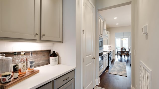 kitchen featuring gray cabinetry, appliances with stainless steel finishes, dark hardwood / wood-style flooring, and backsplash