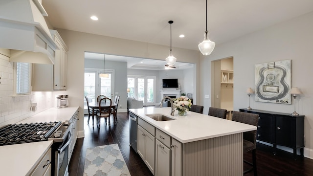 kitchen with sink, a breakfast bar, a kitchen island with sink, stainless steel appliances, and decorative light fixtures