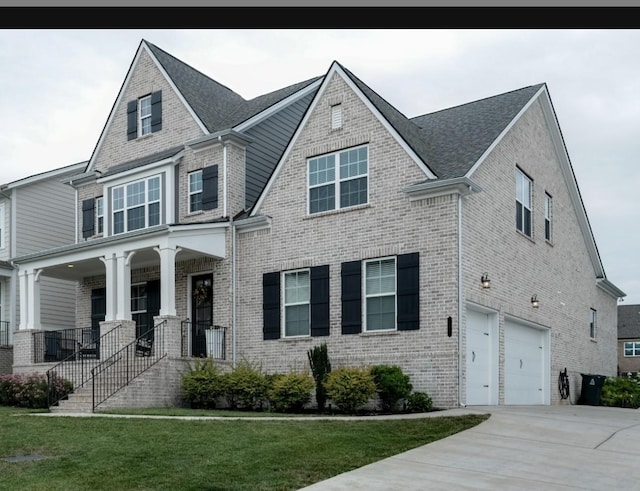 view of front of property with a garage, a front yard, and covered porch