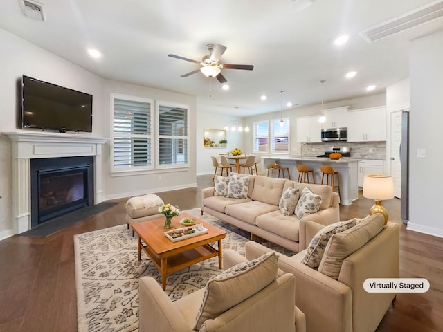 living room featuring dark wood-type flooring and ceiling fan