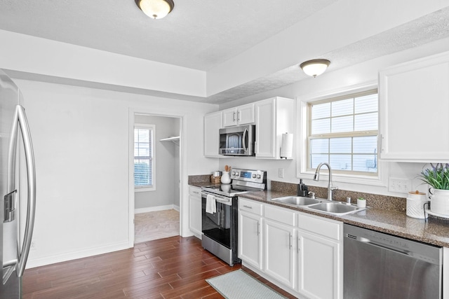 kitchen featuring dark hardwood / wood-style floors, sink, white cabinets, stainless steel appliances, and a textured ceiling