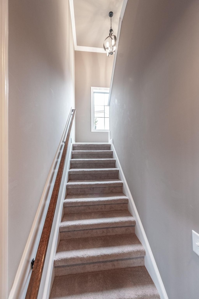 stairs featuring an inviting chandelier and crown molding