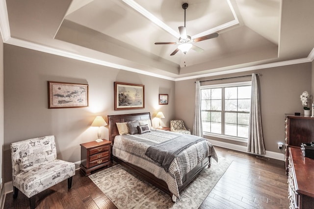 bedroom with crown molding, dark hardwood / wood-style floors, and a raised ceiling