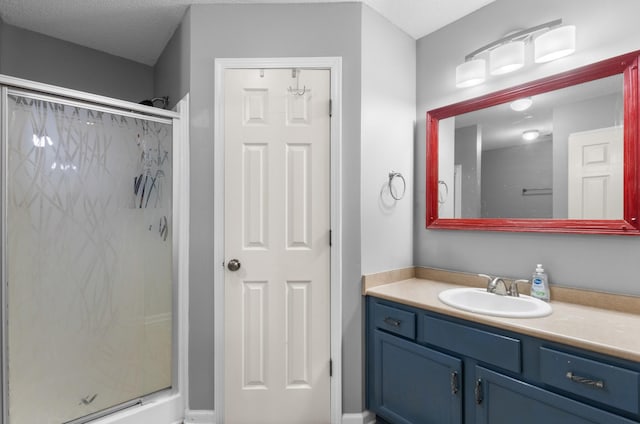 bathroom featuring vanity, a shower with shower door, and a textured ceiling