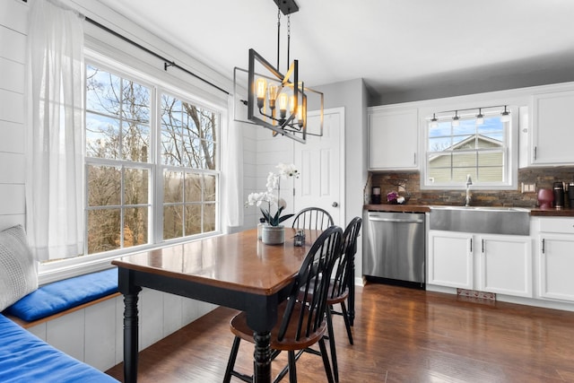 dining space featuring sink, a notable chandelier, and dark hardwood / wood-style flooring