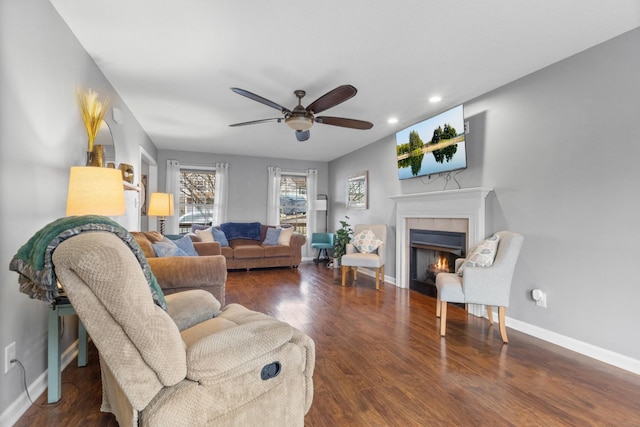 living room with a tiled fireplace, ceiling fan, and dark hardwood / wood-style flooring