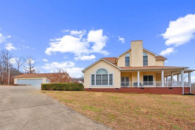 view of front of property with a garage, an outbuilding, covered porch, and a front lawn