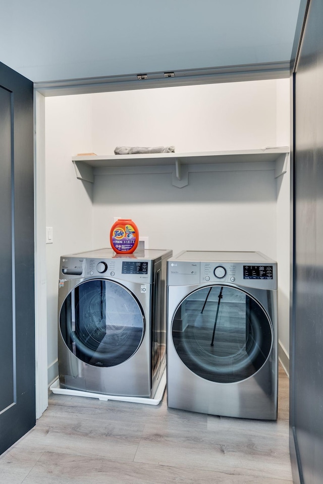 laundry area featuring washing machine and clothes dryer and light hardwood / wood-style floors