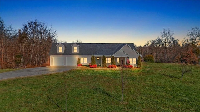 cape cod home featuring a garage and a yard