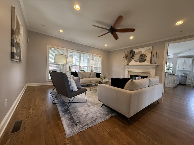 living room featuring visible vents, crown molding, baseboards, ceiling fan, and dark wood-style flooring