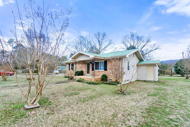 ranch-style home featuring metal roof, brick siding, crawl space, a shed, and a front yard