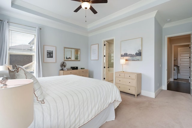 bedroom with connected bathroom, a tray ceiling, light colored carpet, and ceiling fan