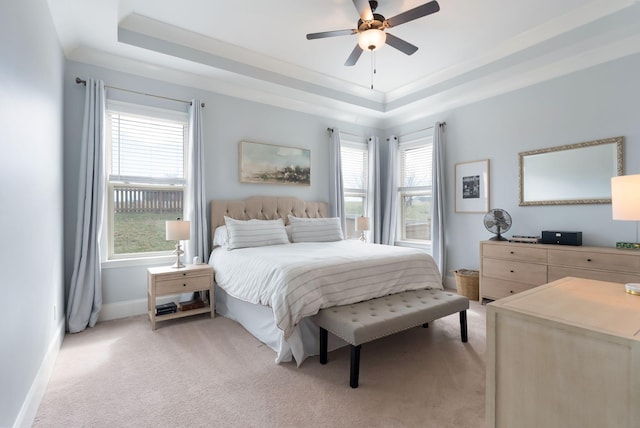 bedroom featuring light colored carpet, ceiling fan, and a tray ceiling