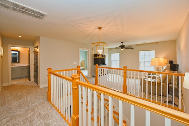 hall featuring light colored carpet and a chandelier