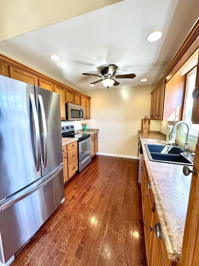 kitchen featuring sink, dark hardwood / wood-style flooring, ceiling fan, stainless steel appliances, and light stone countertops